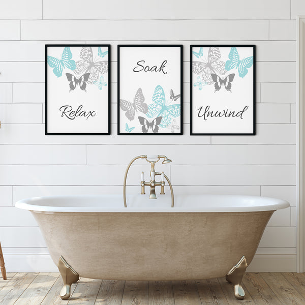 Set of 3 bathroom wall art prints in light teal and grey featuring butterflies and the words "Relax", "Soak", and "Unwind" – perfect spa-inspired decor for a calming, minimalist bathroom or home spa.