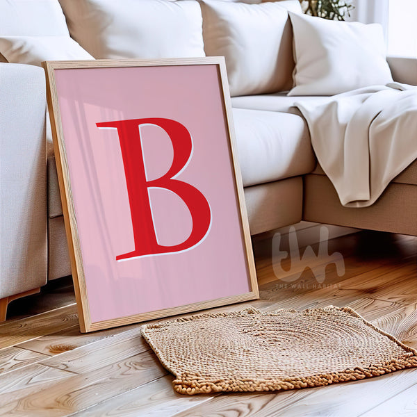 Custom monogram wall art print with a bold red letter 'B' on a pink background, displayed on a wooden tray – personalized alphabet print for home décor