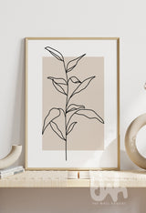 Minimalist line art print of a leafy plant stem, illustrated in black over a warm beige rectangular background, styled in a modern interior setting.