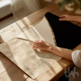 Person holding a goemetric abstract print on a wooden table with sunlight casting shadows