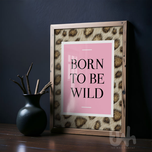 Framed print with 'Born to Be Wild' text on a pink background, leaning against a dark wall.