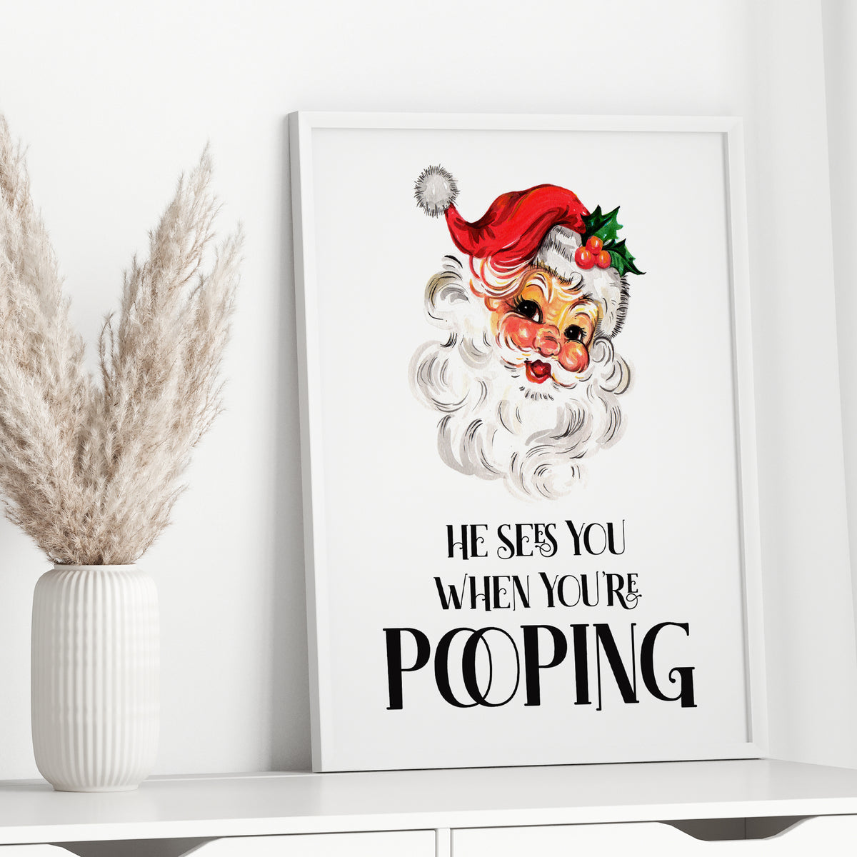 Funny Christmas bathroom wall art featuring vintage Santa and He Sees You When You're Pooping quote in a white frame