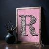 Personalised leopard print initial wall art with pink background displayed in a modern interior