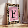 Personalised pink leopard initial wall art print featuring a bold letter on a blush background in a gold frame.