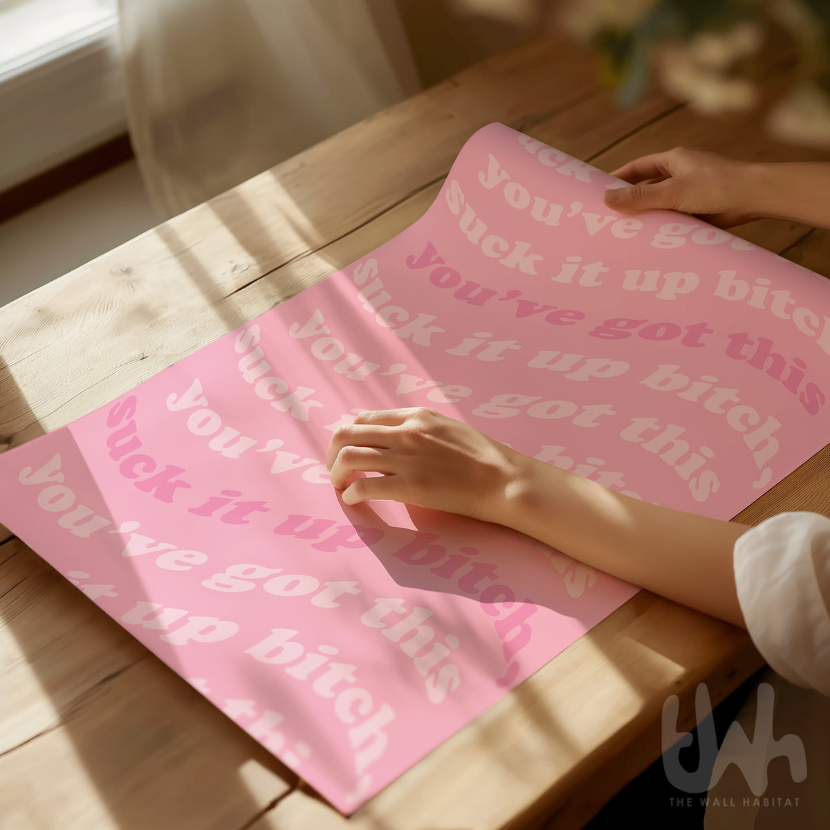 Hand unrolling a pink motivational art print with “Suck it up bitch” and “You’ve got this” text.