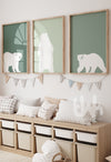 Set of three framed sage green polar bear wall art prints hanging above a toy storage bench in a neutral kids’ room
