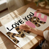 Love you more leopard print wall art with pink typography in styled interior