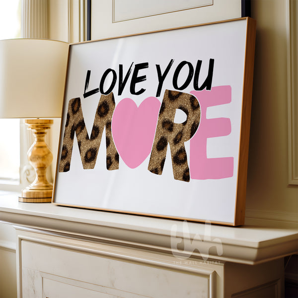 Framed artwork with 'LOVE YOU MORE' text on a mantelpiece.