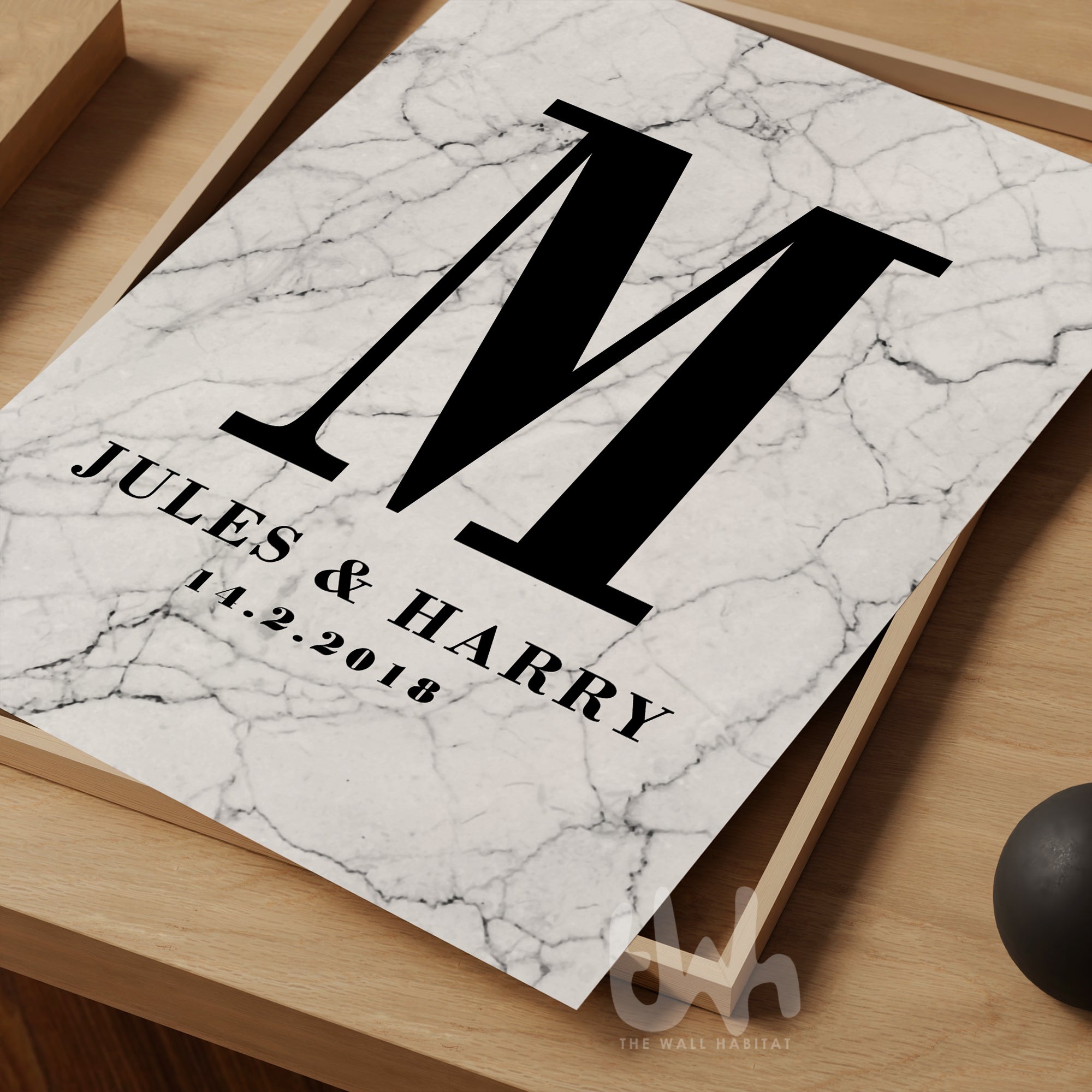 Marble wall art print with a bold black letter 'M', the names 'Jules & Harry', and the date '14.2.2018' printed below, styled on a wooden tray