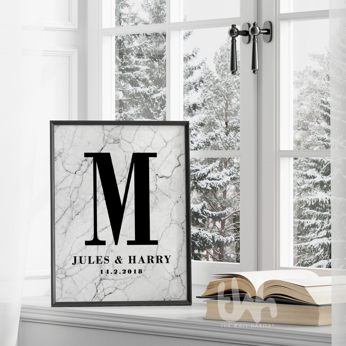 Framed marble personalized couple’s monogram wall print with the letter M, names Jules & Harry, and wedding date, displayed on a windowsill in a winter setting