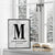 Framed marble personalized couple’s monogram wall print with the letter M, names Jules & Harry, and wedding date, displayed on a windowsill in a winter setting