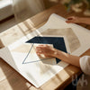 Person holding a geometric design print on a wooden table