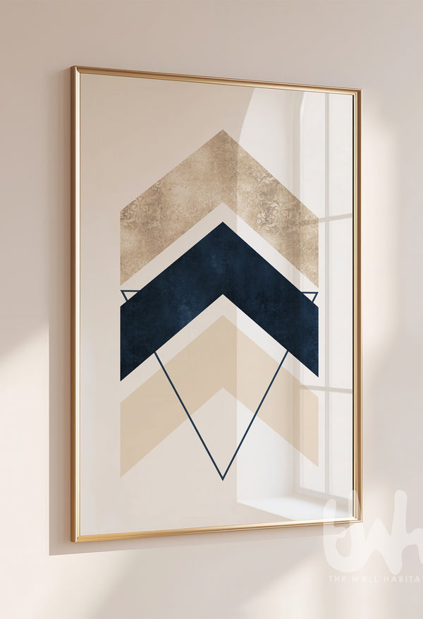 Modern abstract chevron wall art with layered navy blue, beige, and cream arrow shapes and triangle outlines, styled in a gold frame on a neutral wall.