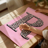Personalised leopard print initial wall art with pink background displayed in a modern interior