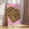 Heart-shaped artwork with leopard print design on a pink background, framed in a light wood color.
