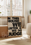 Decorative sign in a living room with text 'In this house we listen & we do judge'.