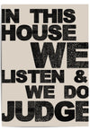 Close-up of "In This House We Listen & We Do Judge" bold typographic wall art on neutral background