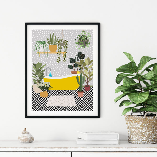 Framed yellow bathtub wall art featuring houseplants and patterned flooring, displayed above a white cabinet in a modern home