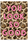 You Look So Good leopard print wall art with pink typography displayed in a gold frame in a modern interior