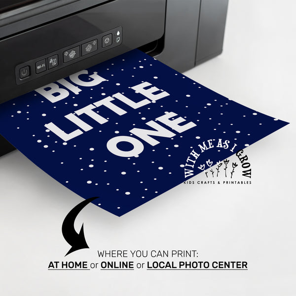 A dark navy blue custom print with white text reading 'BIG LITTLE ONE' and white speckled dots, shown emerging from a printer. promotional text at the bottom about printing at home, online, or locally.