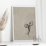 Framed black bow artwork on a beige backdrop, styled on a white console with neutral dried florals – minimalist chic wall décor