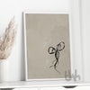 Framed black bow artwork on a beige backdrop, styled on a white console with neutral dried florals – minimalist chic wall décor