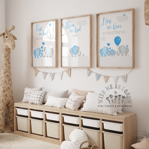 Three framed nursery art prints with blue elephant illustrations and inspirational quotes are displayed on a wall above a wooden storage bench with pillows in a styled nursery room.