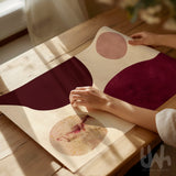 Burgundy abstract printable wall art being prepared for framing on a wooden table