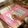 Pink poster with 'Good Vibes Only' text on a wooden surface