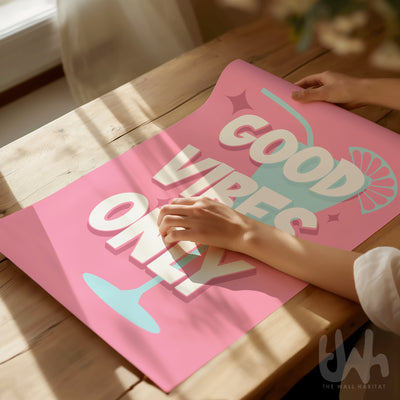 Pink poster with 'Good Vibes Only' text on a wooden surface