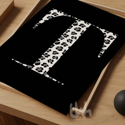 Personalized monogram wall art featuring a bold serif letter 'T' in black and white leopard print on a solid black background, styled on a wooden tray