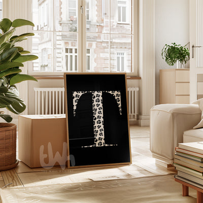 Personalized monogram wall art featuring a bold serif letter 'T' in black and white leopard print on a solid black background, styled in a wooden frame