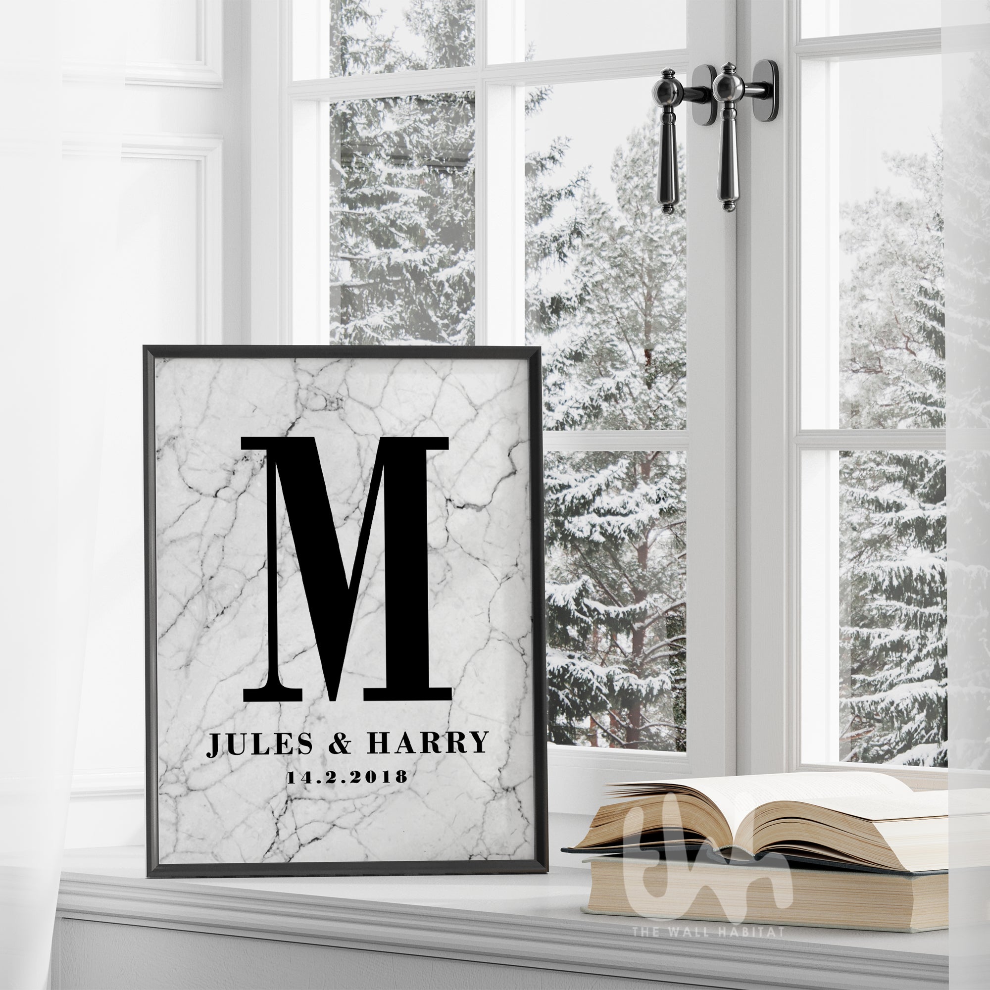 Framed marble personalized couple’s monogram wall print with the letter M, names Jules & Harry, and wedding date, displayed on a windowsill in a winter setting