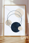 Abstract wall art with overlapping navy, beige, and cream circles and thin intersecting rings, framed and styled in a modern minimalist interior.