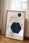 Modern abstract wall art with layered navy, beige, and cream hexagons outlined with geometric navy blue linework, framed in a minimalist home setting.