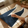 Person holding a blue and beige poster design on a wooden table