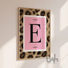 Personalised pink leopard initial wall art print featuring a bold letter on a blush background in a gold frame.