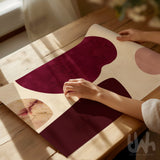 Burgundy abstract printable wall art being prepared for framing on a wooden table