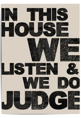 Close-up of "In This House We Listen & We Do Judge" bold typographic wall art on neutral background