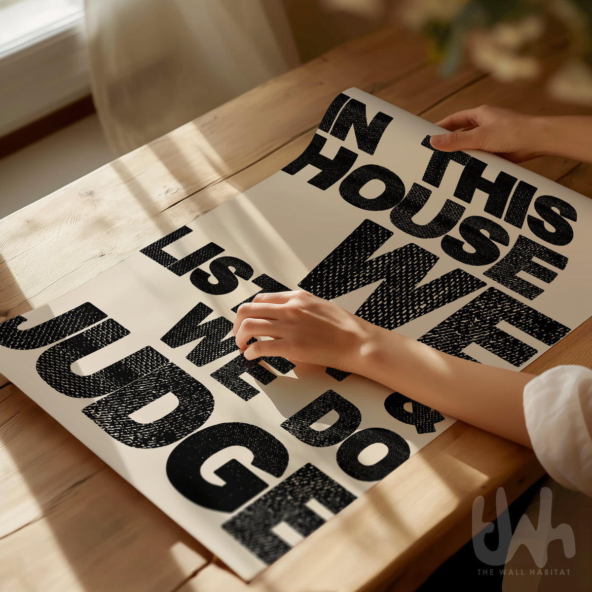 Person unrolling a humorous modern poster on a wooden table with natural light