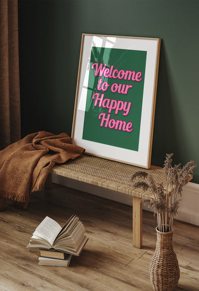 Bold wall art print with pink retro-style text reading 'Welcome to Our Happy Home' on a green background – perfect for cheerful home décor