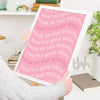 Person holding a framed pink poster with printed text in a home setting