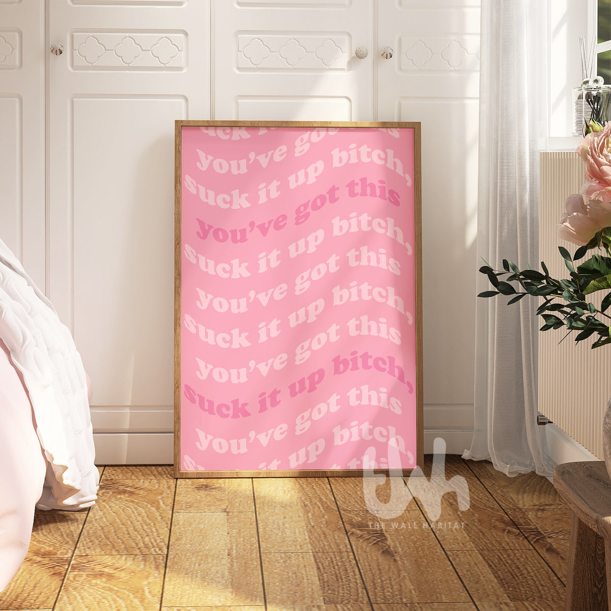 Pink poster with offensive language in a room with wooden floor and white walls.