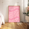 Pink poster with offensive language in a room with wooden floor and white walls.
